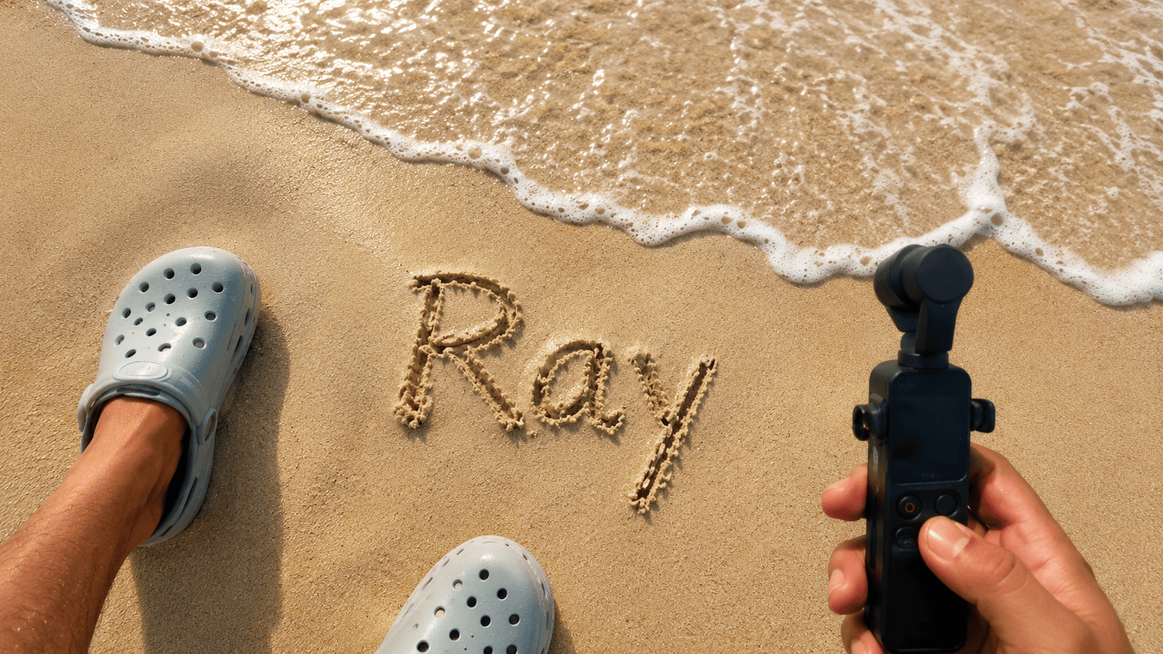 Creator wearing Crocs and holding Insta360 camera with a name written in the sand